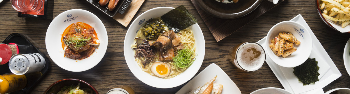 top-down view of ramen, beef, appetizers, and beer